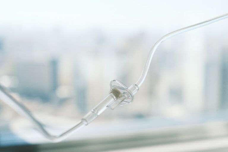 Nahaufnahme eines durchsichtigen Nasenkanülenschlauchs, der für die Sauerstoffzufuhr verwendet wird, mit einer verschwommenen Stadtlandschaft im Hintergrund.
