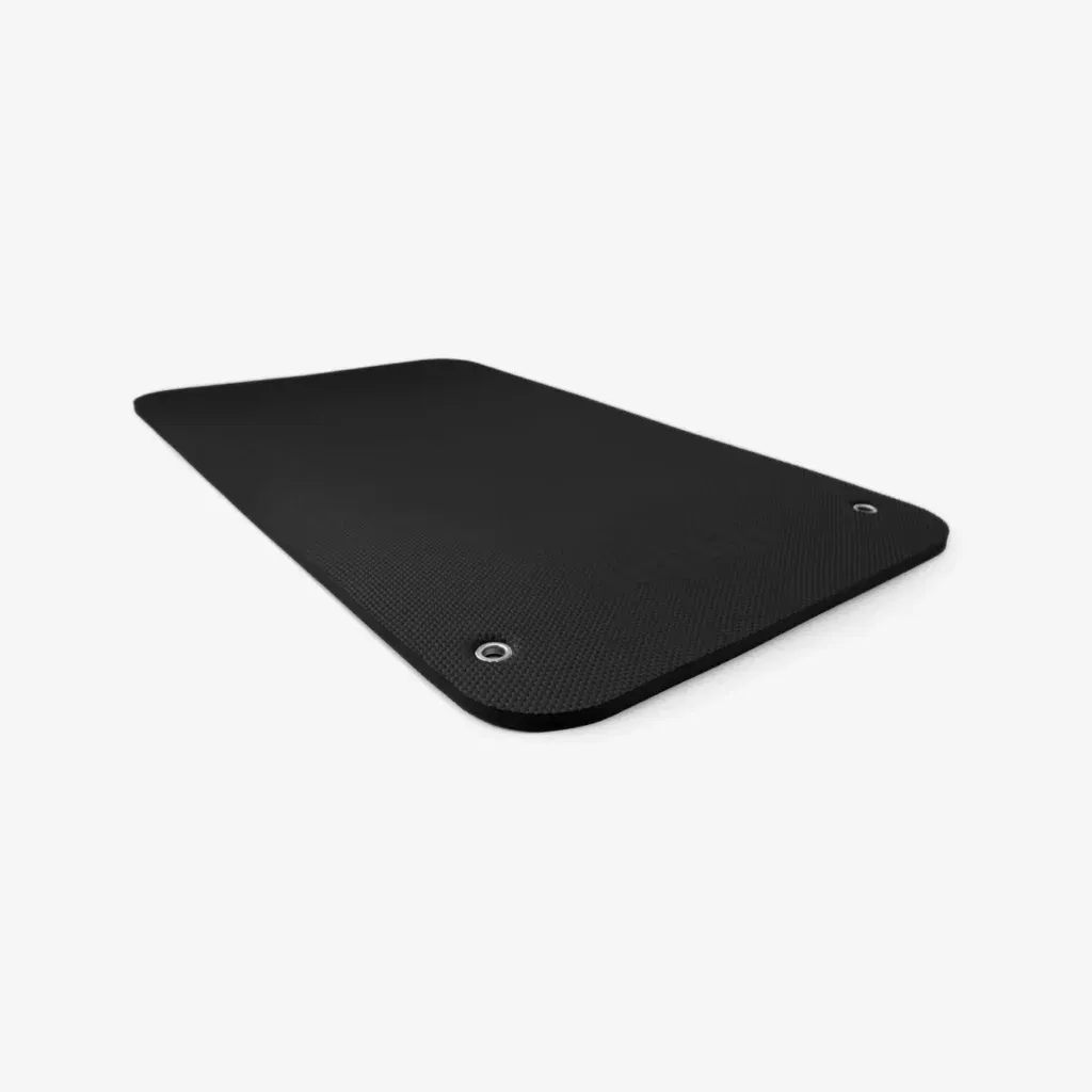 Eine schwarze Übungsmatte mit zwei metallverstärkten Löchern in den Ecken, abgebildet auf weißem Hintergrund. Die Matte hat eine leicht strukturierte Oberfläche und abgerundete Kanten.