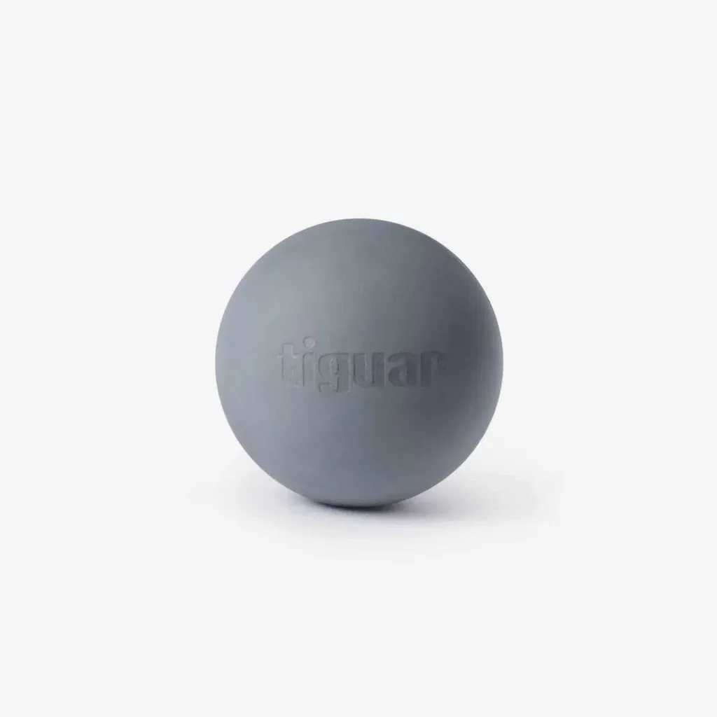 Ein grauer Massageball, auf dessen Oberfläche das Wort Tiguar eingeprägt ist, steht auf einem schlichten weißen Hintergrund.