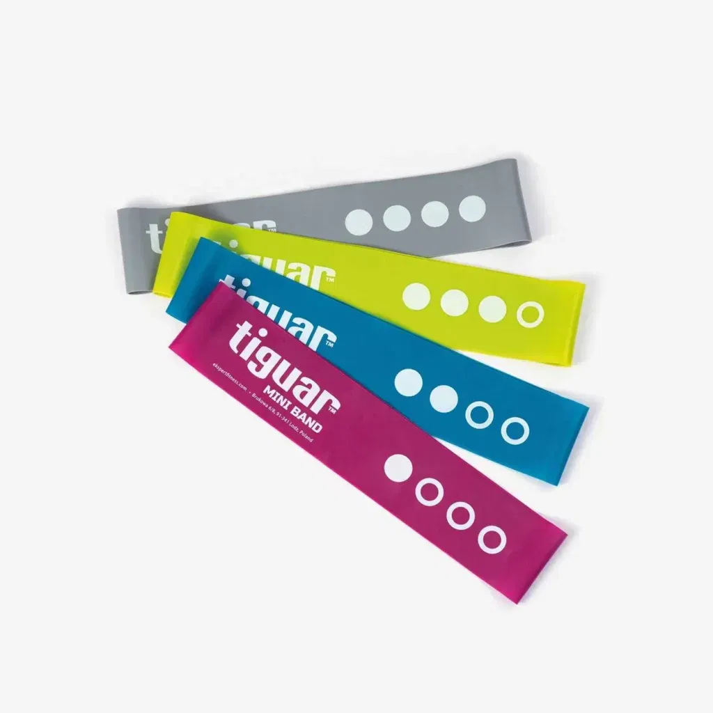 Vier flache Widerstandsbänder in Grau, Gelb, Blau und Rosa, die jeweils mit tiguar MINI BAND und einer Reihe weißer Kreise, die verschiedene Widerstandsstufen angeben, beschriftet sind, sind überlappend auf einem weißen Hintergrund angeordnet.