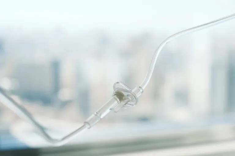 Nahaufnahme eines durchsichtigen Nasenkanülenschlauchs, der für die Sauerstoffzufuhr verwendet wird, mit einer verschwommenen Stadtlandschaft im Hintergrund.