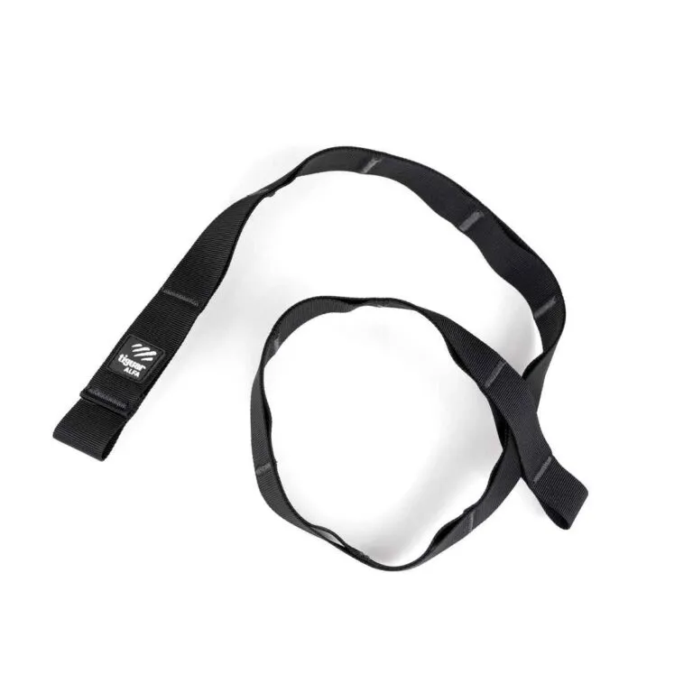 Ein schwarzes Nylonband mit aufgenähten Schlaufen, die sich in einem losen Kreis auf weißem Hintergrund aufrollen. An einem Ende des Bandes ist ein kleines schwarz-weißes Etikett mit einem Logo angenäht.