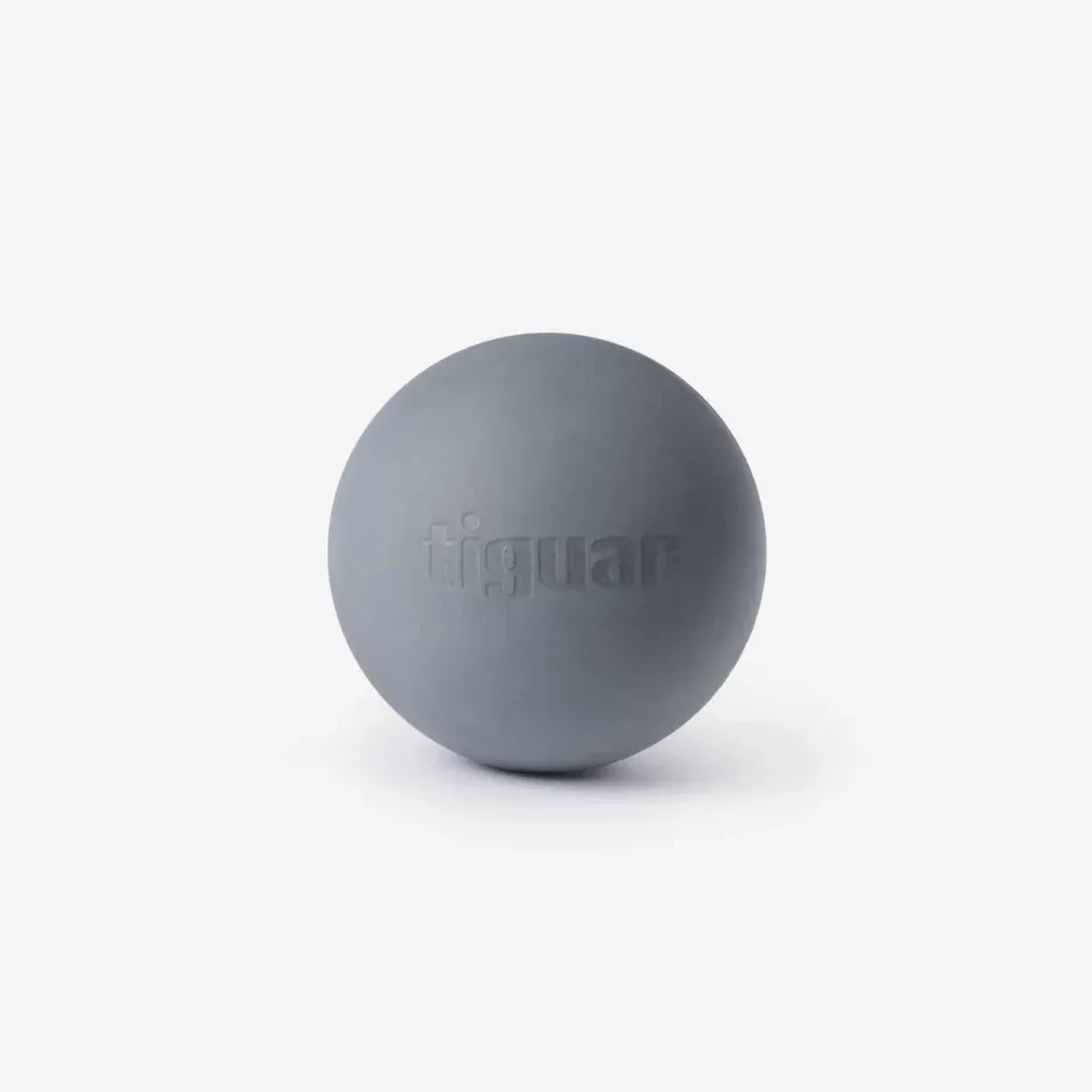 Ein grauer Massageball, auf dessen Oberfläche das Wort Tiguar eingeprägt ist, steht auf einem schlichten weißen Hintergrund.