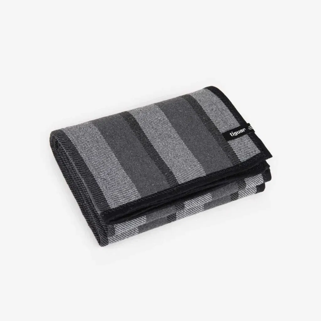 Ein gefaltetes graues Portemonnaie mit schwarzen und hellgrauen horizontalen Streifen, mit einem kleinen schwarzen Anhänger am Rand.